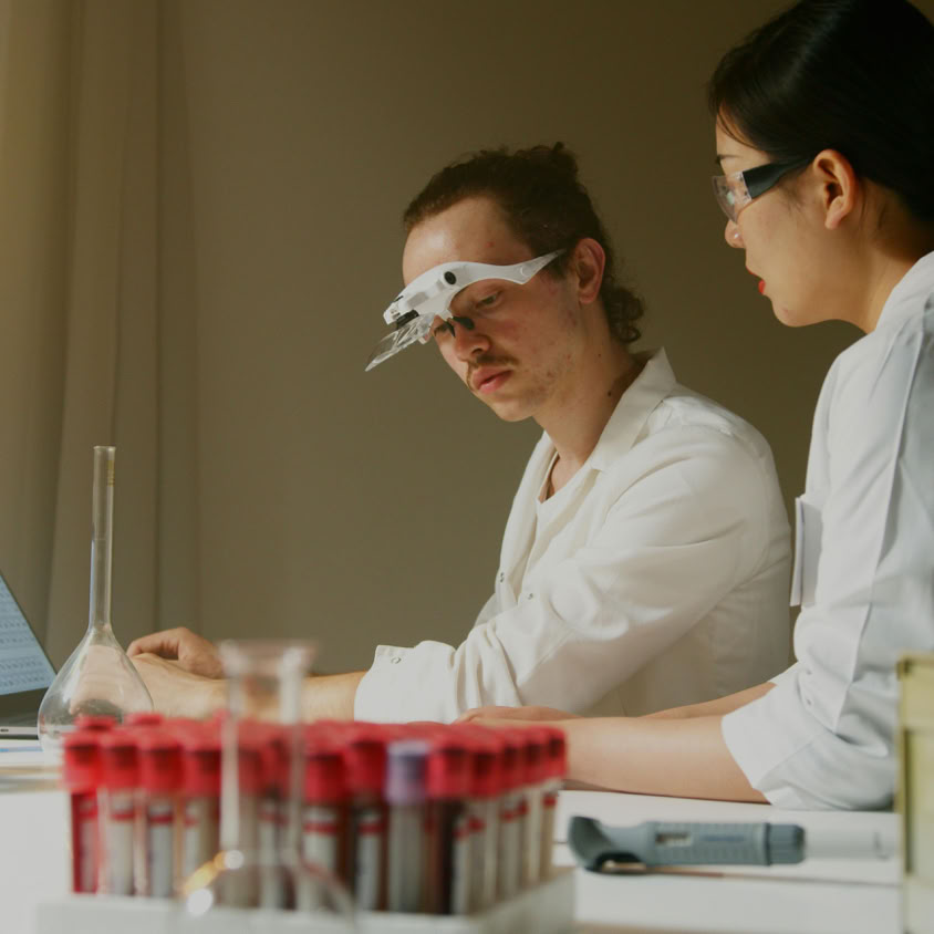 Researchers analyzing samples in a laboratory, surrounded by equipment and test tubes.