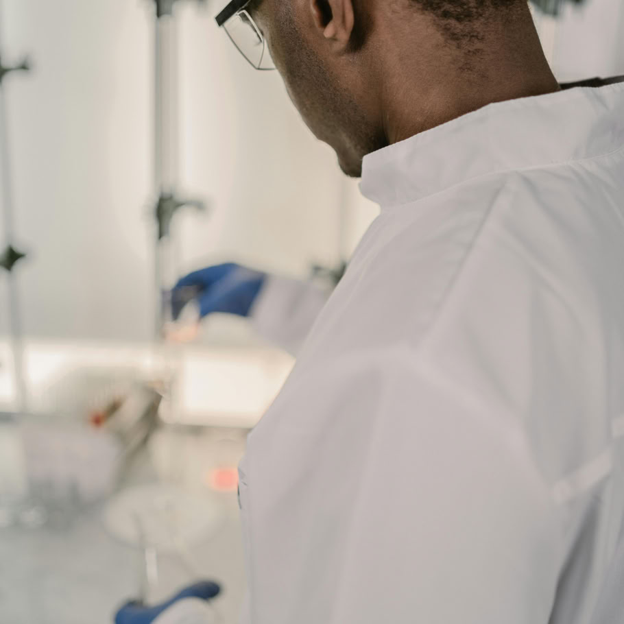 Research scientist in lab coat conducting experiments in a laboratory setting, focused on chemical reactions.